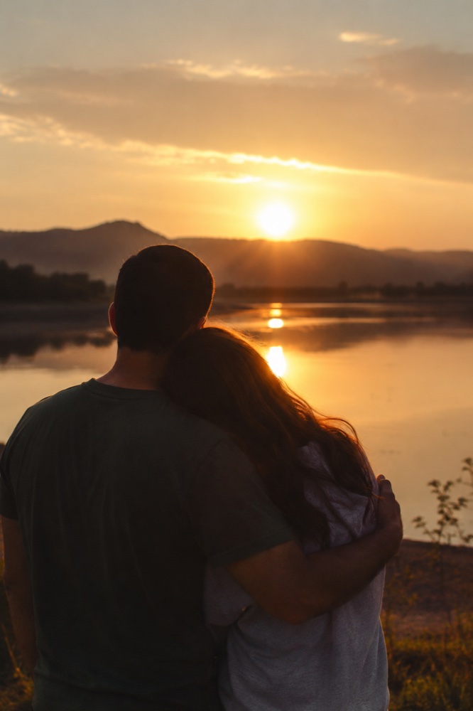 Un matrimonio abrazado contemplando el atardecer